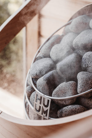 Electric sauna heater stones with 'HUUM' branding on a blurred background