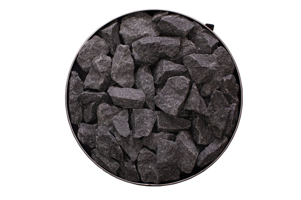 Round sauna heater filled with dark gray stones on a white background