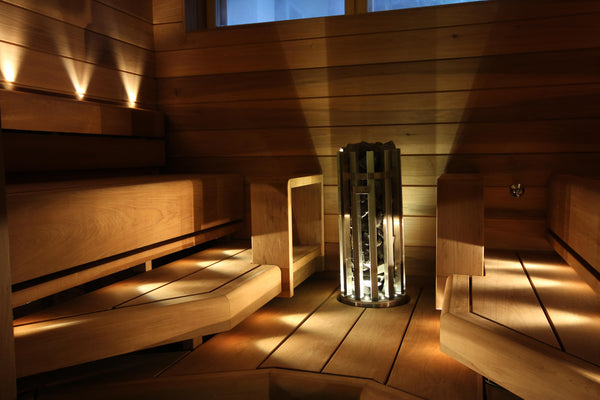 Wooden sauna interior with benches and a central light fixture.