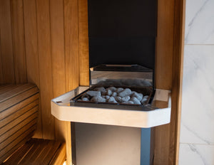 Sauna interior with wooden benches and a stone-lined sauna heater.