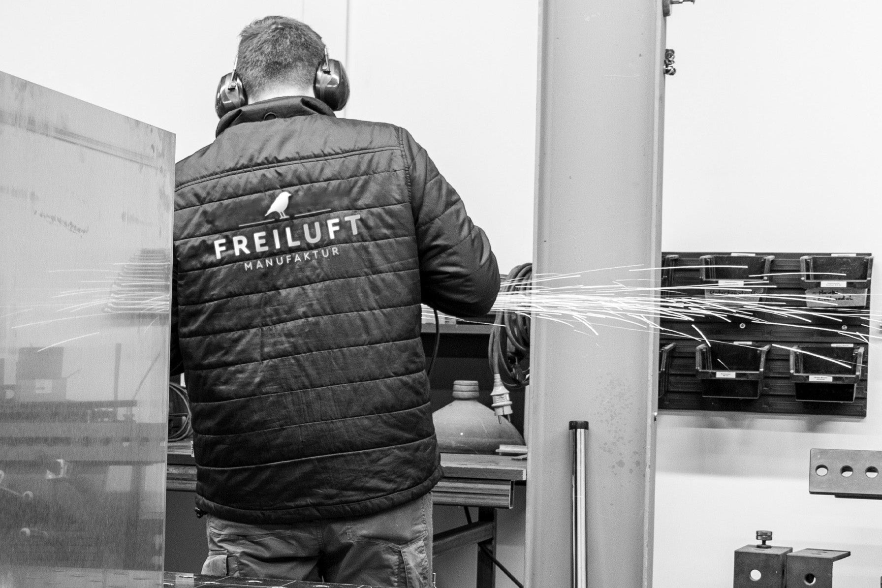 Person wearing a jacket with 'Freiluft' branding in a workshop setting.