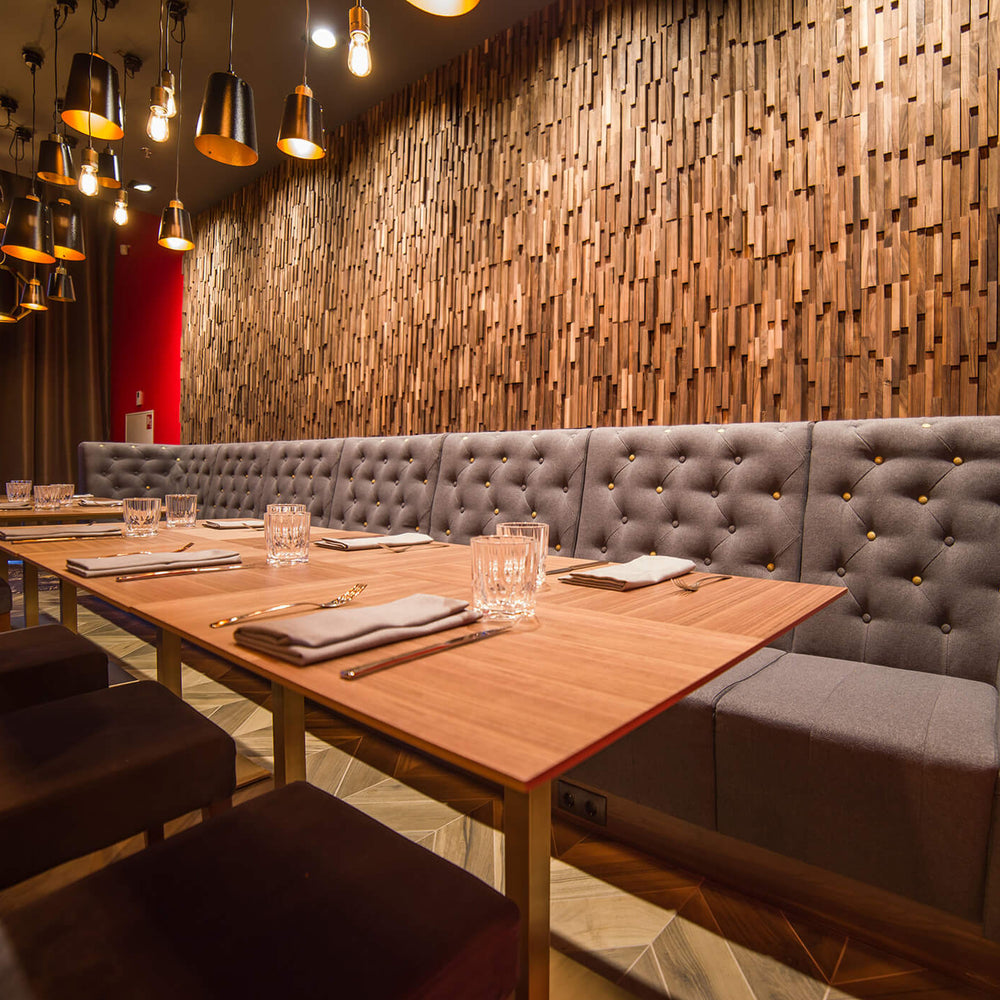 Dining area with wooden tables and gray booths against a wooden EmotionWood wall.