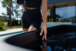 Person in black swimwear standing by a cold plunge