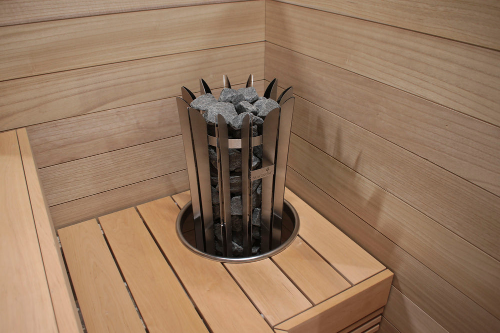 Wooden sauna with a metal basket containing stones on a wooden platform.