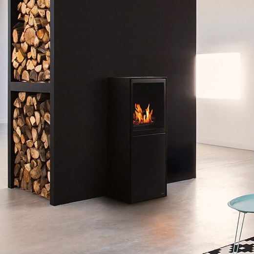 Planika Scandi free-standing ethanol fireplace next to a black wall with logs inside. 