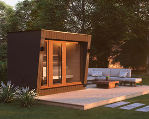 Render of Saunum AirCube Space outdoor sauna outside on a wooden terrace with a lounge couch and table at sunset.