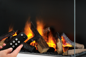 Hand holding a remote control in front of a fireplace with flames and logs.