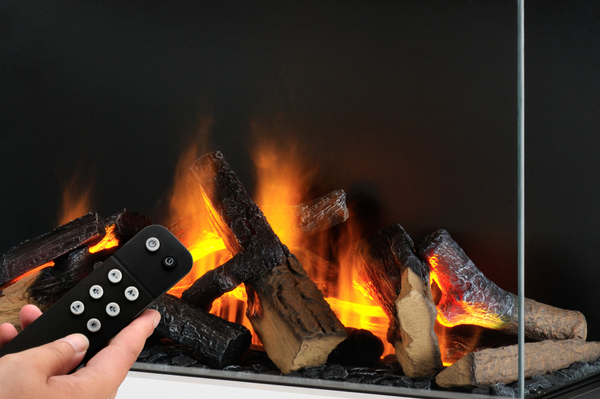 Hand holding a remote control in front of a fireplace with flames and logs.