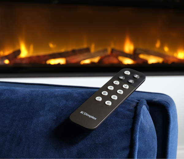Remote control on a blue armchair with a fireplace in the background