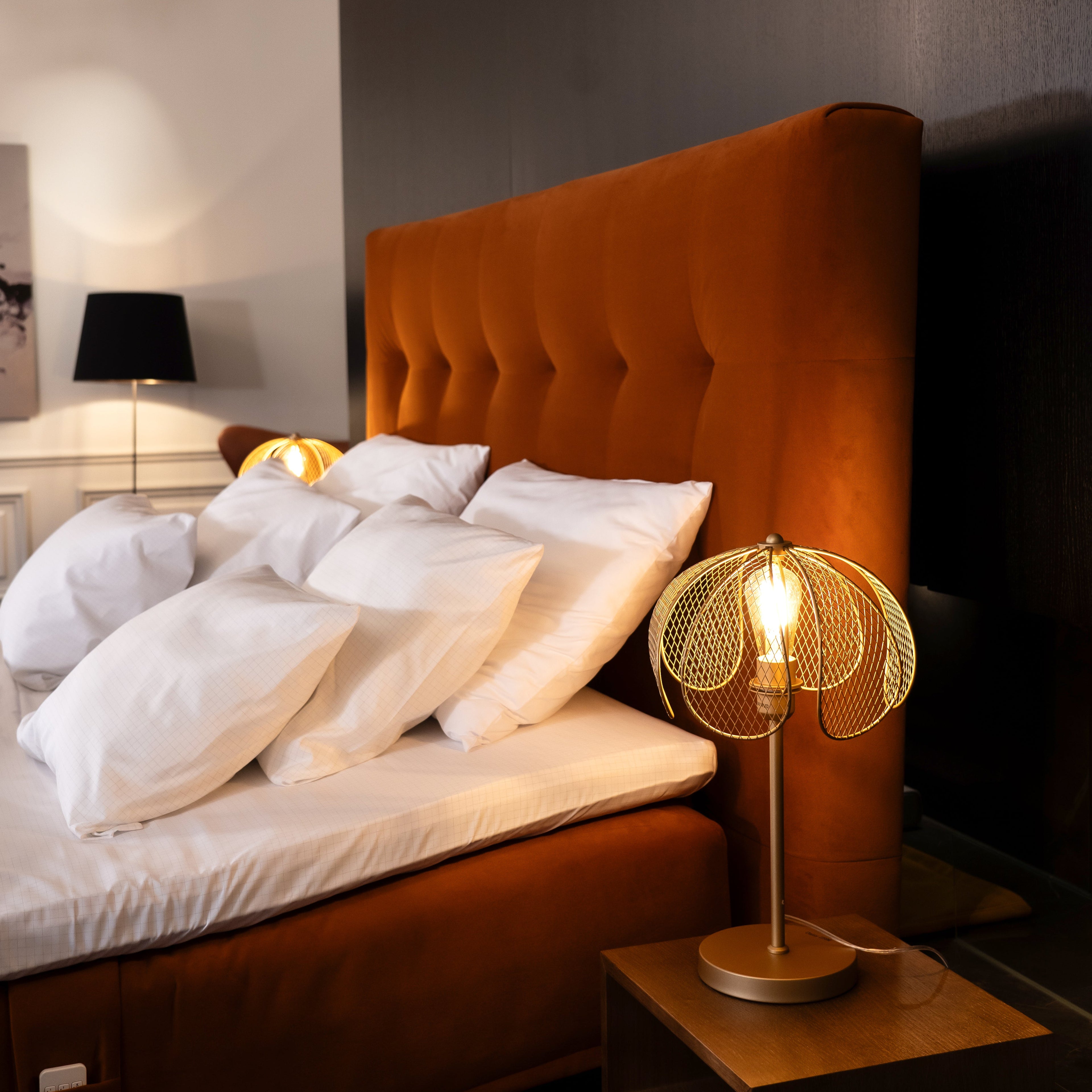 Bedroom with orange upholstered headboard and gold table lamp on nightstand
