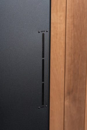 Close-up of a black Electric sauna heater with a wooden panel on the right