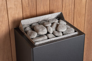 HUUM black electric sauna heater with grey stones in a wooden sauna