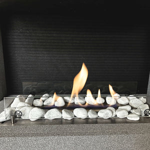 Modern gas fireplace with lit flames and decorative stones on a dark background
