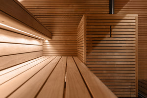 Wooden sauna interior with slatted walls and bench.