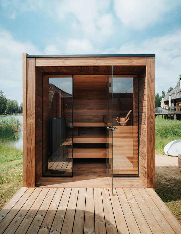 Wooden outdoor sauna with glass door in a natural setting