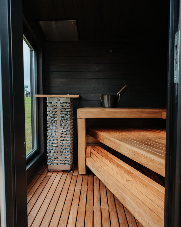 Wooden sauna interior with benches and a basket.
