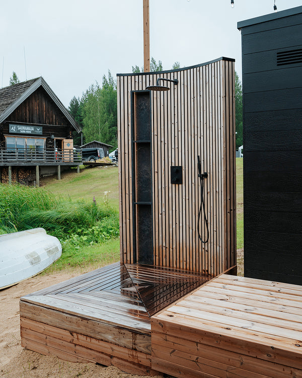 Wooden outdoor shower with a rustic cabin in the background