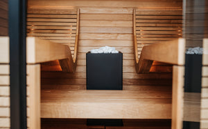 Wooden sauna with two benches and a central fire pit.