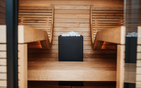 Wooden sauna with two benches and a central fire pit.