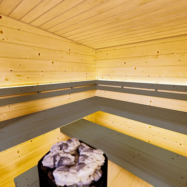 Wooden sauna interior with a bench and stone heater.