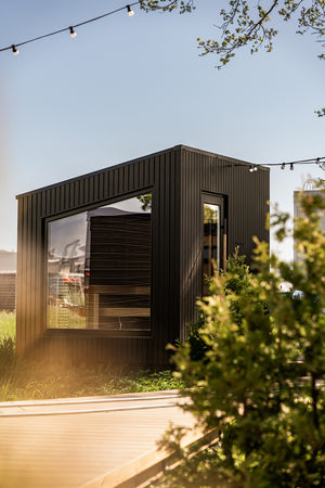 Modern black modular building with glass windows in a natural setting