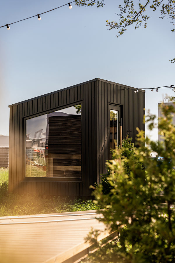 Modern black modular building with glass windows in a natural setting