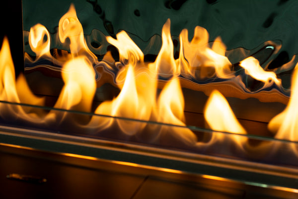 Close-up of flames in a fireplace with a reflective surface.