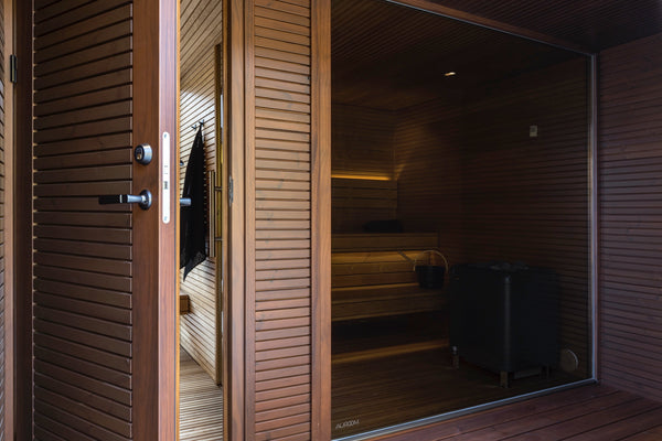Wooden sauna door with glass panel open, revealing a dimly lit interior.