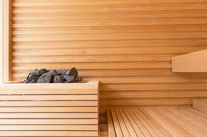 Wooden sauna interior with a bench and stone heater.