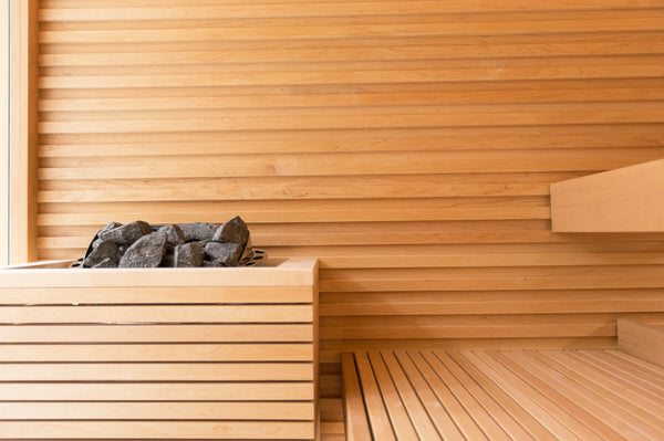 Wooden sauna interior with a bench and stone heater.