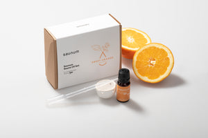 Saunum Sweet Orange essential oil set with a box, bottle, and sliced oranges on a light background