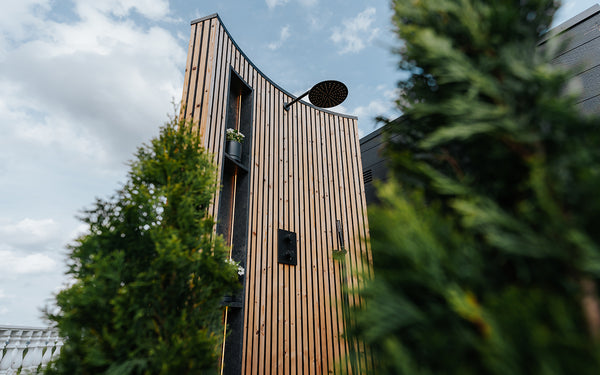 Wooden building with a modern design, surrounded by greenery under a blue sky.