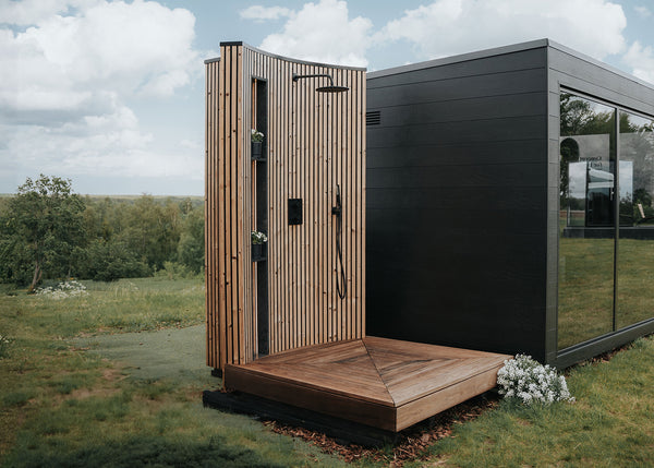 Modern outdoor shower with wooden paneling in a grassy area