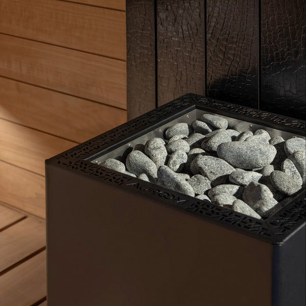Wooden sauna interior with a stone-lined sauna heater.